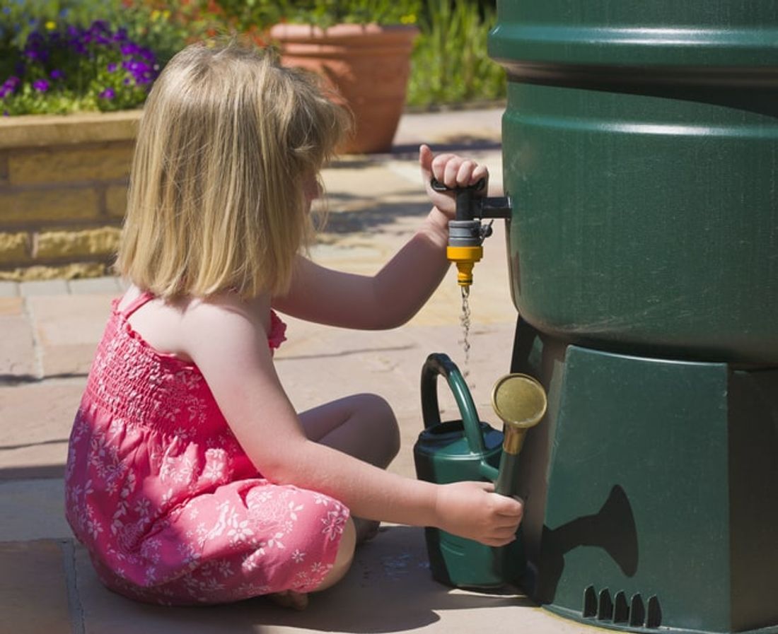 Young girl collecting water from a rainwater tank