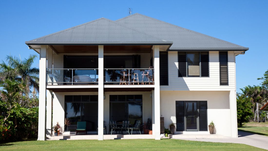Tidy two story family beach side home with a colorbond roof, with blue sky and green grass, Queensland Australia