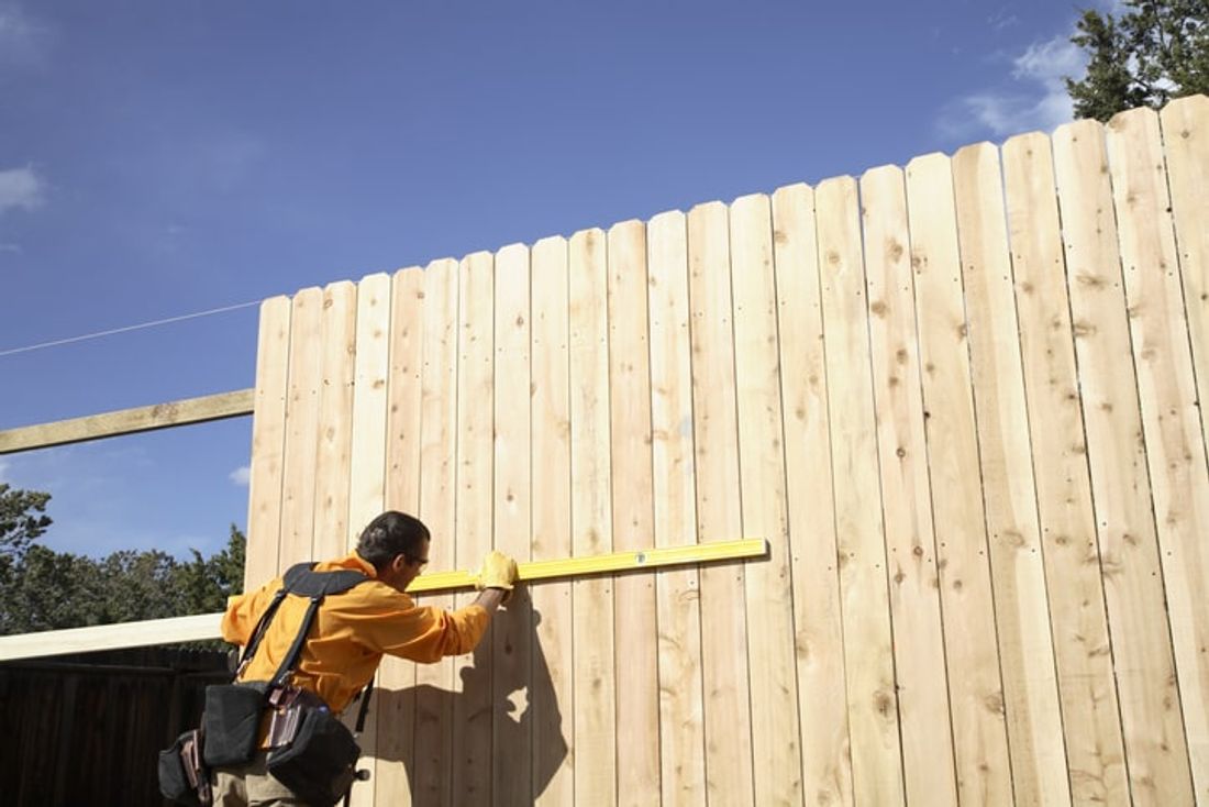 tradie installing wooden fencing