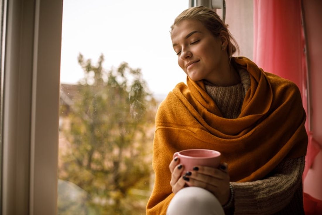 woman enjoying her warm home with a mug of tea
