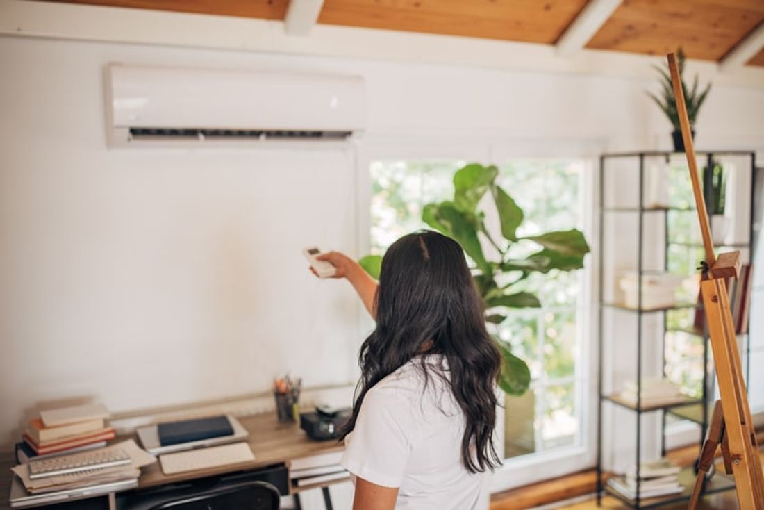Woman adjusting split type aircon thermostat