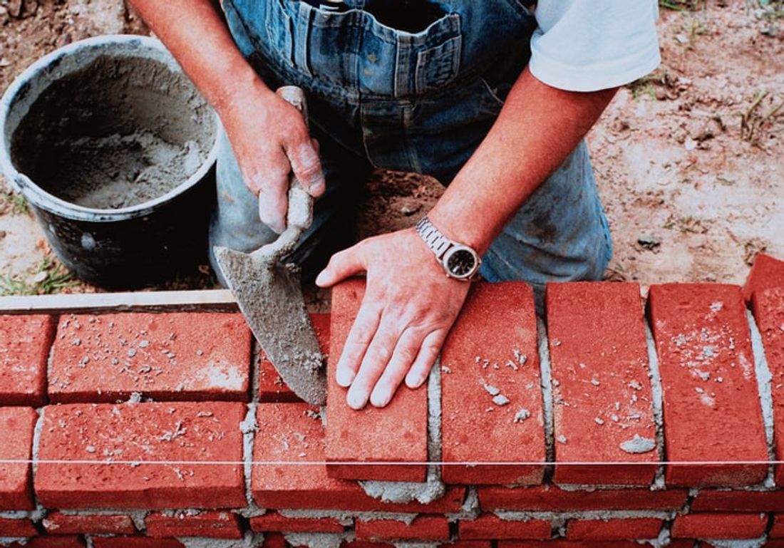 handyman laying down red bricks