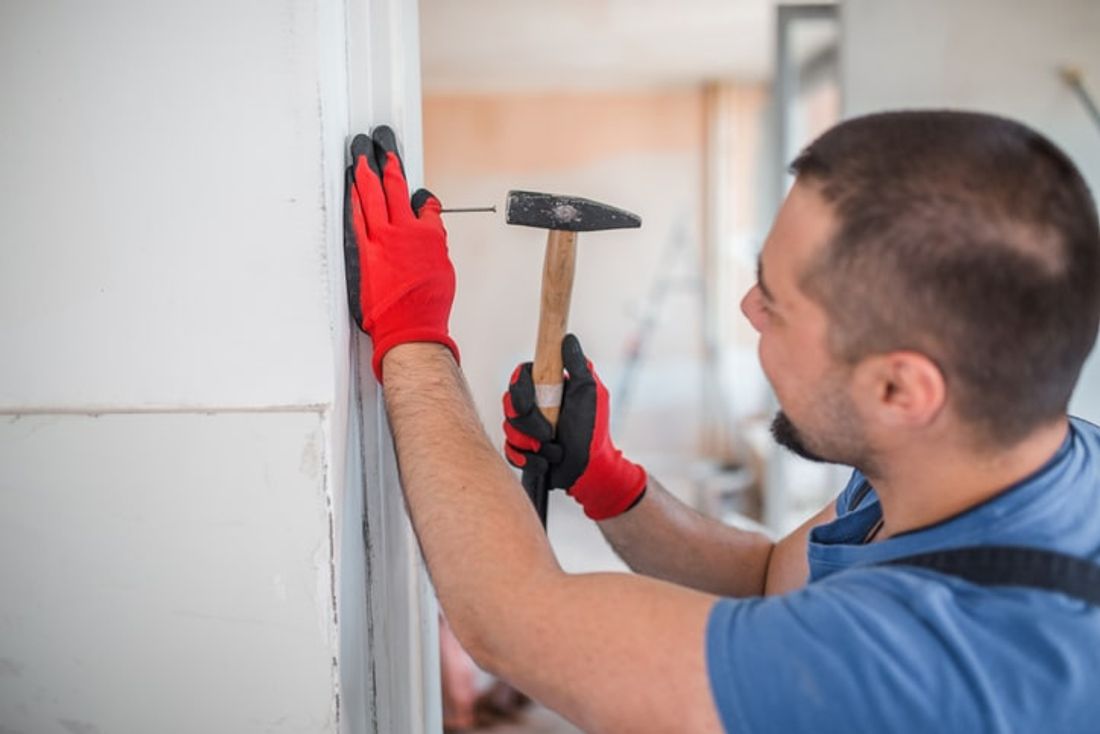 handyman hammering nails into a wall