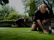 two synthetic turf installers laying down patches of artificial grass 